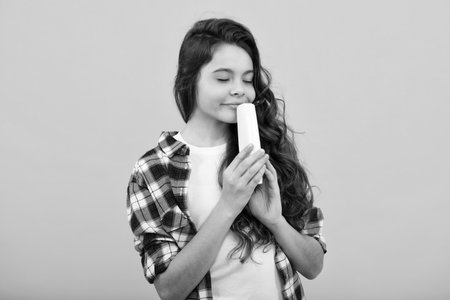 Teen child girl with shampoo bottle or shower gel isolated on yellow background. Kids hair cosmetic product.の写真素材