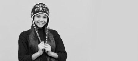 smiling child in winter hat on yellow background, knitwear. Banner of christmas child girl, studio...