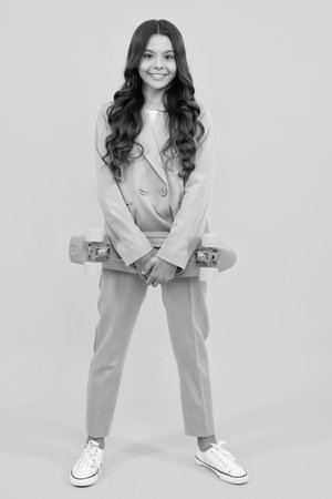 Teen girl 12, 13, 14 years old with skateboard over studio background. Cool modern teenager in stylish clothes. Teenagers lifestyle, casual youth culture.の写真素材