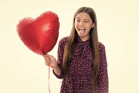 Funny face. Lovely child girl 12, 13, 14 years old with shape heart balloon, love holiday and valentine symbol. Valentine or birthday day.の写真素材