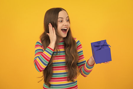 Teenager child with gift box. Present for holidays. Happy birthday, Valentines day, New Year or Christmas. Kid hold present box. Excited face, cheerful emotions of teenager girl.の写真素材