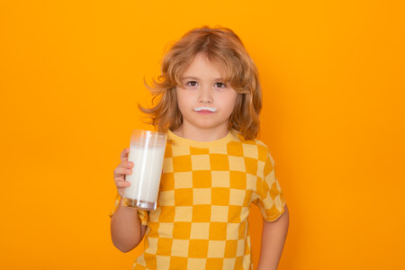 Healthy food for kids. Organic milk. Child with glass of milk, isolated on yellow studio background.の写真素材
