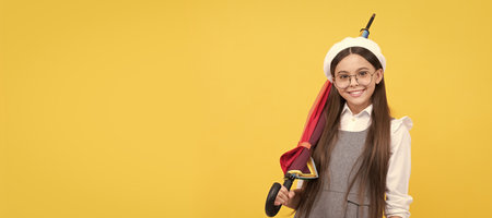 happy teen girl in glasses and beret hold colorful umbrella for rain protection in autumn, fall. Child with autumn umbrella, rainy weather, horizontal poster, banner with copy space.の写真素材