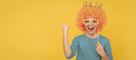 cheerful child girl in curly wig and princess diadem wear party glasses, success. Funny teenager child in wig, party poster. Banner header, copy space.の写真素材