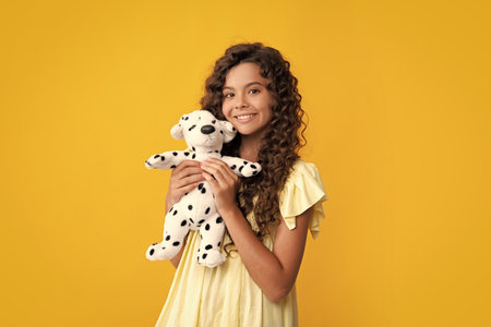 Teen girl child in casual wear holding plush toy isolated on yellow background, happy childhood. Happy teenager, positive and smiling emotions of teen girl.の写真素材