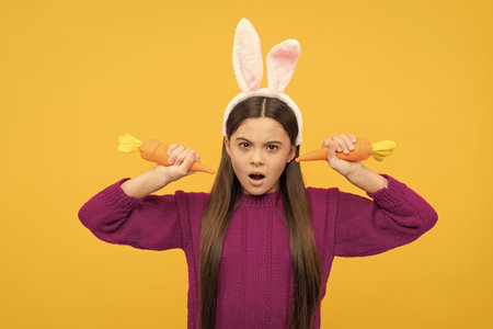 amazed easter teen girl in funny bunny ears hold carrot, happy easterの写真素材