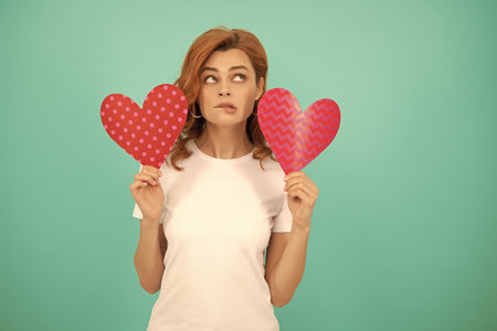 pondering young woman with red heart on blue backgroundの写真素材