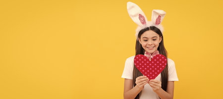 happy easter child girl in bunny ears and bow tie hold love heart. Easter child horizontal poster. Web banner header of bunny kid, copy space.の写真素材
