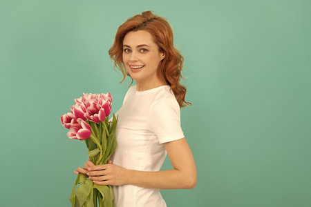 happy cheerful woman with tulip flower bouquet on blue backgroundの写真素材