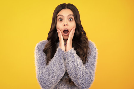Happy teenager, positive and smiling emotions of teen girl. Teenager child girl with shocked facial expression. Surprised face expression, isolated on yellow background. Funny surprise.の写真素材
