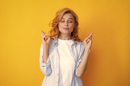Portrait of funny woman with crossed fingers for good luck, isolated background. Woman crosses fingers with positive expression, believes in good luck and success. Female student, young teacher.の写真素材