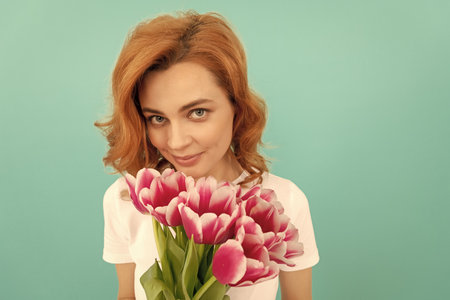 woman portrait with tulip flower bouquet on blue backgroundの写真素材