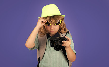 Kids travel. Happy child boy in travel hat with photo camera isolated on studio backgraund. Travel lifestyle and dreams of travel.の写真素材
