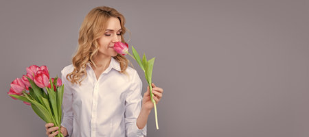 cheerful blonde woman with spring tulip flowers on grey background. Woman isolated face portrait, banner with mock up copy space.の写真素材