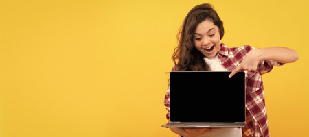teen girl pointing finger on laptop on head. online education. back to school. webinar advertisement. School girl portrait with laptop, horizontal poster. Banner header with copy space.の写真素材
