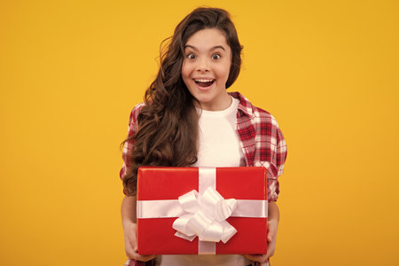 Amazed teenager. Emotional teenager child hold gift on birthday. Funny kid girl holding gift boxes celebrating happy New Year or Christmas. Excited teen girl.の写真素材