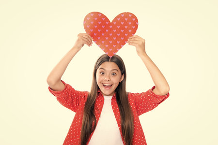 Lovely romantic teenage girl hold red heart symbol of love for valentines day isolated on white background. Portrait of emotional amazed excited teen girl.の写真素材