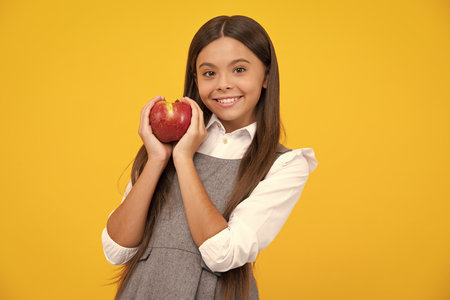 Fresh fruit. Teenager girl hold apples on yellow isolated studio background. Child nutrition. Happy girl face, positive and smiling emotions.の写真素材