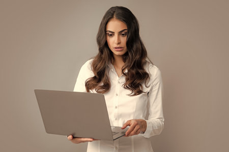 Pretty assistant holding notebook search information internet. Young business woman with laptop computer isolated studio portrait on gray background. Freelancer at work.の写真素材