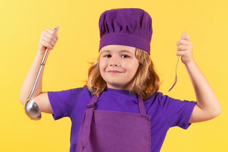Funny kid chef cook with kitchen ladle, studio portrait. Child chef cook. Child wearing cooker uniform and chef hat preparing food, studio portrait.の写真素材