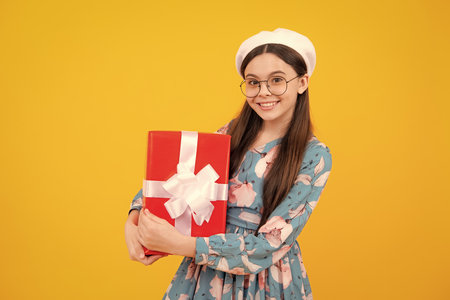 Child teen girl 12-14 years old with gift on isolated background. Birthday, holiday concept. Teenager hold present box. Happy teenager, positive and smiling emotions.の写真素材