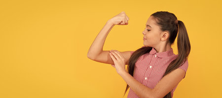 Girl power. Female child flex arm yellow background. Gesture of power and strength. Child face, horizontal poster, teenager girl isolated portrait, banner with copy space.の写真素材