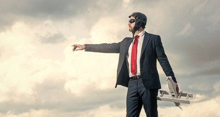 businessman in suit and pilot hat launch plane toy on sky background. think bigの写真素材