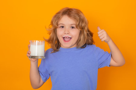 Healthy drink with calcium and protein for kids. Little boy drinking milk. Child with glass of milk on yellow isolated background.の写真素材