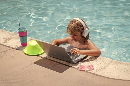 Child with laptop in swimming pool in summer day. Work outside concept, Business and summer.の写真素材