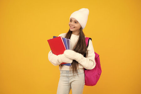 Funny school girl child student with backpack and hat, isolated yellow background. Learning and knowledge education concept. Autumn school.の写真素材