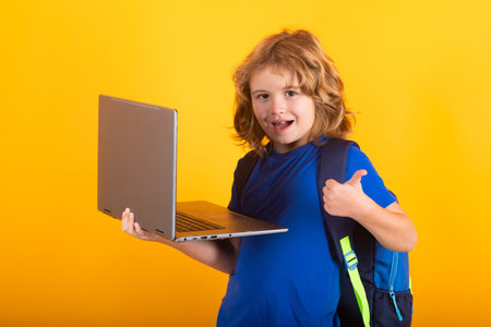 School child using laptop computer. Kid boy from elementary school with book. Little student, smart nerd pupil ready to study. Concept of education and learning.の写真素材