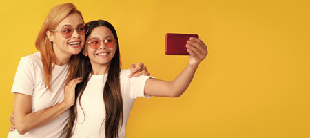 Mother and daughter child banner, copy space, isolated background. smiling mom and kid making selfie on smartphone, fun.の写真素材