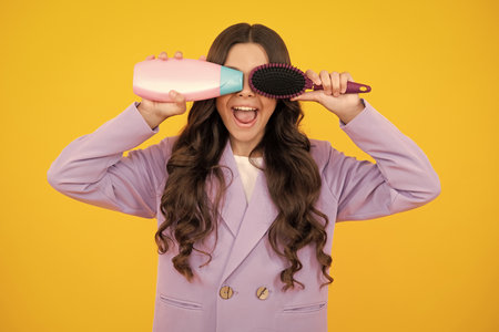 Teenager child girl showing bottle shampoo conditioners or shower gel. Hair cosmetic product. Bottle for advertising mock up copy space. Excited teenager girl.の写真素材