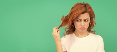 unhappy redhead woman with curly hair on blue background, disappointment. Woman isolated face portrait, banner with copy space.の写真素材