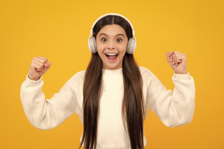 Child music concept. Teenager child girl dances in rhythm of melody, listens song in headphones. Child listening to music through earphones.の写真素材