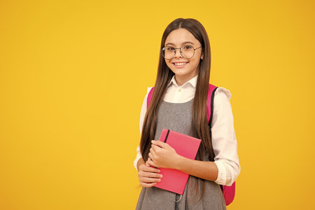 Schoolgirl with copy book posing on isolated background. Literature lesson, grammar school. Intellectual child reader.の写真素材