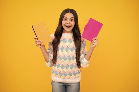 Back to school. Teenager schoolgirl with book ready to learn. School girl children on isolated yellow studio background.の写真素材