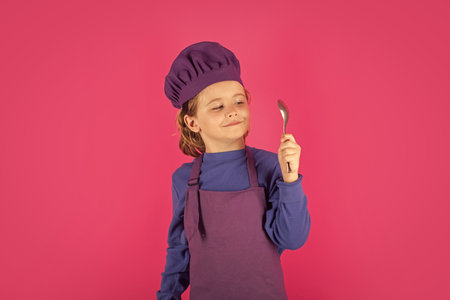 Child cook hold spoon. Cooking children. Chef kid boy making healthy food. Portrait of little child in chef hat isolated on studio background. Kid chef. Cooking process.の写真素材