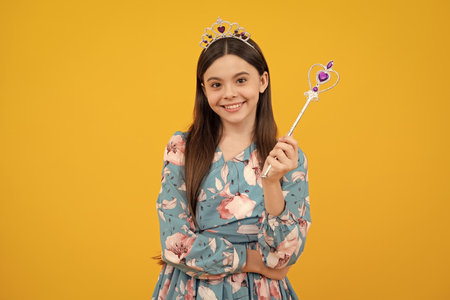 Beautiful fairytale princess on yellow background. Romantic wonderland story. Little fairy girl with crown and magic wand putting spell.の写真素材