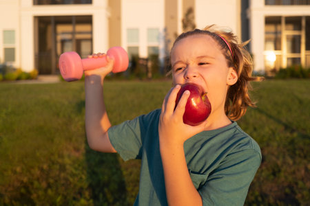 Kids sport training outdoor. Kid boy working out with dumbbells. Sport and kids training.の写真素材