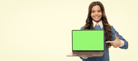happy kid portrait make presentation point finger on laptop isolated on white, presentation. School girl portrait with laptop, horizontal poster. Banner header with copy space.の写真素材