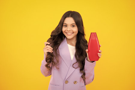 Child teen girl with shampoos conditioners and shower gel. Long hair care of teenager. Presenting cosmetic product, shampoo bottle. Happy teenager, positive and smiling emotions of teen girl.の写真素材