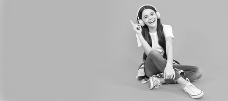 happy teen girl listen to music in wireless headphones. Child portrait with headphones, horizontal poster. Girl listening to music, banner with copy space.の写真素材
