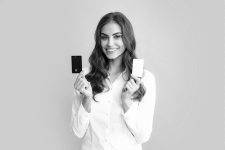 Woman holds template mockup bank credit card with online service isolated on gray background. Happy attractive young girl showing credit.の写真素材