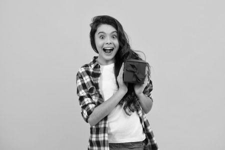 Amazed teenager. Child with gift present box on isolated background. Presents for birthday, Valentines day, New Year or Christmas. Excited teen girl.の写真素材