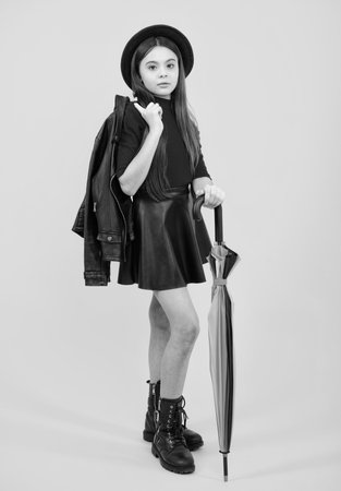 Fashion autumn kids weather. Child teenager girl with rainbow umbrella in autumn isolated on yellow background. Autumn kids trendy clothes.の写真素材