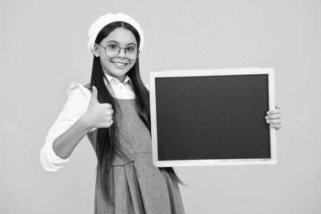 School sales board. Cheerful teenage girl kid hold blackboard chalkboard with copy space. Happy face, positive and smiling emotions of teenager girl.の写真素材