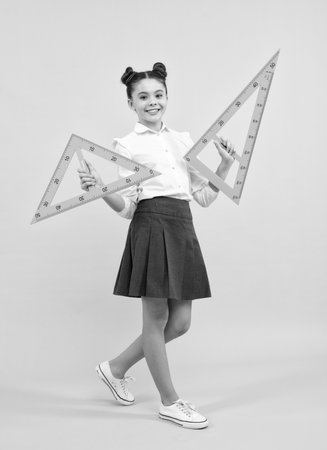 Measuring school equipment. Schoolgirl holding measure for geometry lesson, isolated on blue background. Student study math. Happy teenager, positive and smiling emotions of school girl.の写真素材