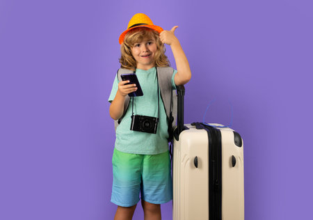 Child traveler with suitcase isolated on studio background. Tourist kid boy. Portrait of child travel with travel bag. Travel, adventure, vacation.の写真素材