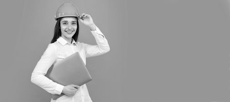 Happy woman in protective hard hat helmet with laptop computer isolated on grey background....
